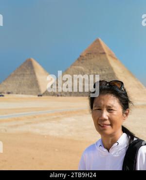Gros plan d'une touriste asiatique debout devant les grandes pyramides de Gizeh ; Gizeh, le Caire, Egypte Banque D'Images