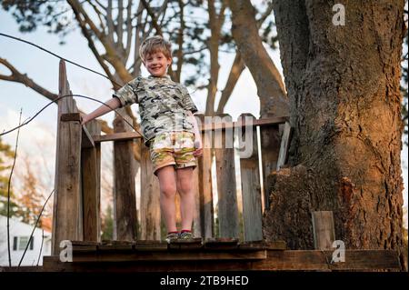 Jeune garçon joue dans sa cabane dans les arbres ; Lincoln, Nebraska, États-Unis d'Amérique Banque D'Images