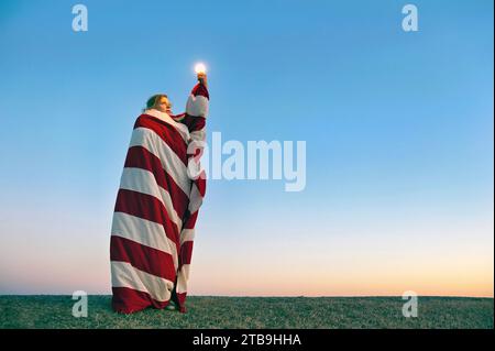 Jeune femme pose comme la statue de la liberté avec une ampoule ; Lincoln, Nebraska, États-Unis d'Amérique Banque D'Images