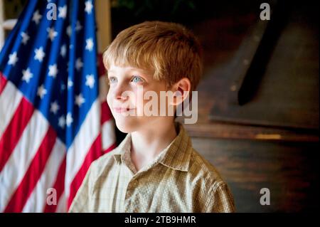 Jeune garçon patriotique debout devant le drapeau américain ; Lincoln, Nebraska, États-Unis d'Amérique Banque D'Images