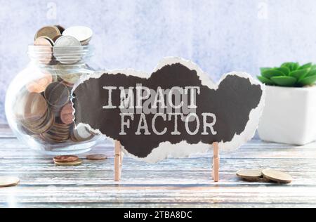 Texte DU FACTEUR D'IMPACT écrit sur fond gris avec un stylo et une calculatrice. Banque D'Images