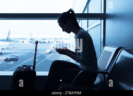 Jeune femme voyageuse à l'aéroport utilisant son smartphone. Banque D'Images