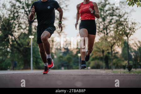 Entraînement de couple actif en plein air dans le parc, jogging ensemble en fin de soirée. Banque D'Images