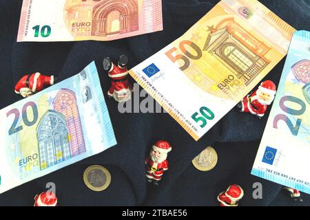 Santa clauses avec des pièces en euros sur une couverture, symbole image pour bonus de fin d'année Banque D'Images