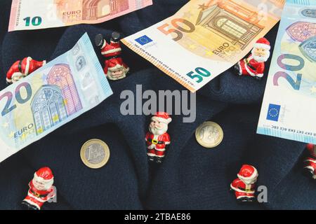 Santa clauses avec des pièces en euros sur une couverture, symbole image pour bonus de fin d'année Banque D'Images