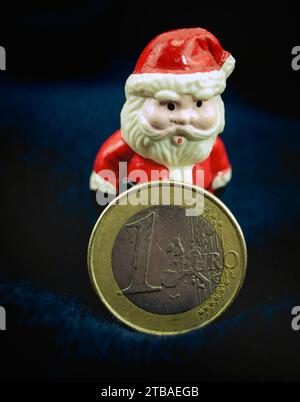 Père Noël avec pièce en euro, symbole image pour bonus de fin d'année Banque D'Images