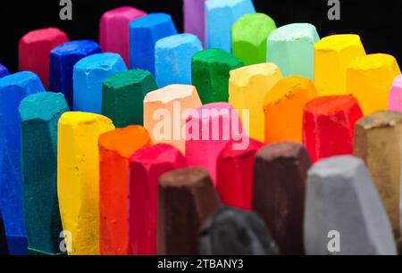 une collection de bâtonnets de crayons soigneusement disposés visibles d'en haut dans une rangée de couleurs colorées Banque D'Images