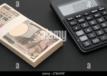 Enveloppe salariale japonaise et calculatrice, les billets sont écrits comme '10 000 yens' en japonais. Banque D'Images