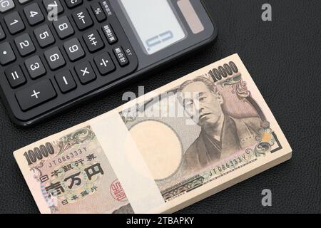 Enveloppe salariale japonaise et calculatrice, les billets sont écrits comme '10 000 yens' en japonais. Banque D'Images
