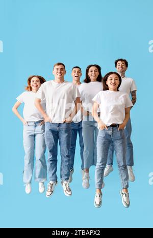 Groupe de jeunes en jeans élégants sautant sur fond bleu Banque D'Images