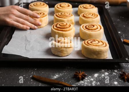 Femme préparant des rouleaux de cannelle à table Banque D'Images