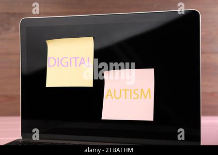 Notes adhésives avec phrase Digital Autism attaché à l'ordinateur portable sur la table, gros plan. Comportement addictif Banque D'Images