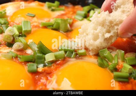 Femme mangeant délicieux Shakshuka avec du pain, gros plan Banque D'Images