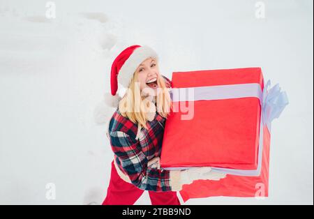 Femmes de service avec grande boîte cadeau. Santa Woman détient une grande boîte cadeau avec espace de copie pour votre texte. Joyeux hiver. Femme portant un grand cadeau isola Banque D'Images