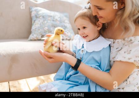 Gros plan de l'élégance jeune maman et tout-petit fille adorable en robe jouant avec de petits canetons jaunes dans la maison gazebo d'été sur la journée ensoleillée Banque D'Images