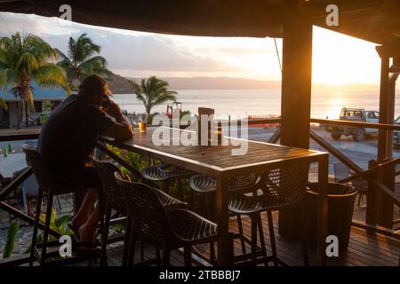 Homme assis à une table buvant de la bière et regardant le coucher du soleil à la Golden Bosun Tavern, un bar et restaurant populaire à Settlement. Christmas Island, Austral Banque D'Images