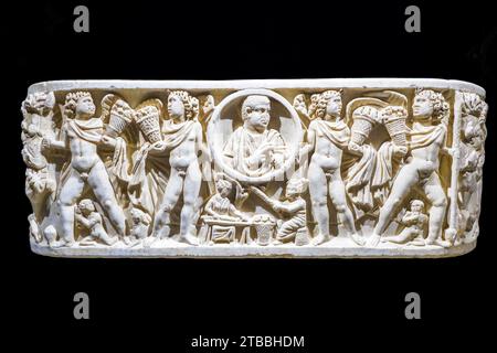 Sarcophage de baignoire avec représentation seulement sur le devant et les côtés incurvés. Un cercle central (clipeus), qui représente le défunt avec un rouleau dans sa main gauche, est soutenu par deux figures masculines ailées qui, jumelées avec d'autres semblables et interprétées comme des personnifications des quatre saisons, tiennent des paniers pleins de fruits abondants et divers. Au centre sous le clypeus, scène de la vie quotidienne. Marbre blanc 3e siècle après JC - Cattedrale di San Gerlando (Cathédrale Agrigente) - Sicile, Italie Banque D'Images