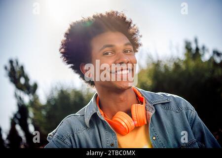 Portrait de belle belle belle joyeuse personne agréable avec chevelure Wear jeans chemise écouteurs toothy souriant en été dans le parc à l'extérieur Banque D'Images