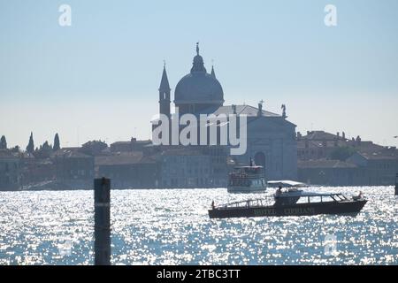 Regarder Chiesa del Santissimo Redentore à Giudecca à travers l'eau étincelante argentée de Bacino di San Marco dans une douce brume bleue de lumière vénitienne Banque D'Images