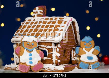 Le pain d'épice de Noël en forme d'hommes est décoré avec un glaçage au sucre coloré et une maison à biscuits. Banque D'Images