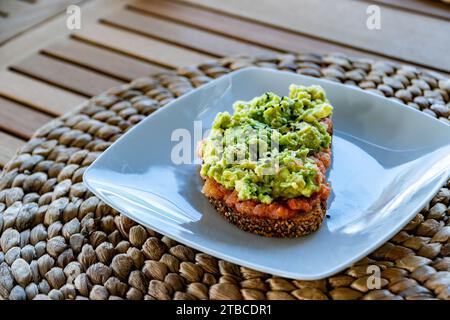 une image en gros plan d'une tranche de pain grillé brun surmontée de tomates râpées et d'avocat écrasé Banque D'Images