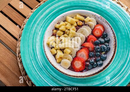 une image en gros plan sur un bol de crème glacée d'açai frais surmonté de fruits frais et de baies sur une table en bois Banque D'Images