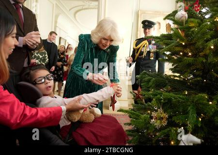 La reine Camilla, accompagnée d'enfants soutenus par Helen and Douglas House et la Marvellous Children's Charity de Roald Dahl, décorent le sapin de Noël de Clarence House à Londres. Date de la photo : mercredi 6 décembre 2023. Banque D'Images