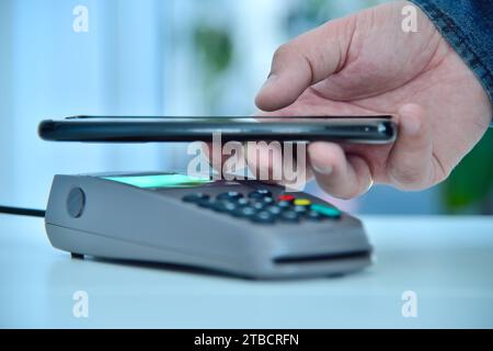 Téléphone à main avec paiement sur le terminal de pos. De carte de paiement. Paiement mobile et concept de shopping en ligne. Gros plan Banque D'Images