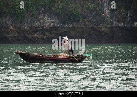 Pêcheur local dans son bateau à rames travaillant sur la baie d'Halong au Vietnam Banque D'Images