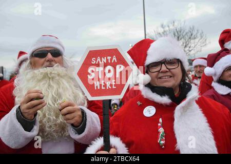 Neustadt an der Weinstrasse, Allemagne . 06 décembre 2023, Rhénanie-Palatinat, Neustadt an der Weinstraße : les motocyclistes habillés en santas se tiennent ensemble et une femme tient un panneau disant "Santa stop here". Les « Harley Davidson Riding Santas » sont « sur la route à nouveau » sur St. Nicholas Day. Les motards collectent des dons pour une bonne cause avec leur campagne annuelle depuis 2015. Cette année, les motocyclistes habillés en Santas avec des chapeaux et des barbes sont sur la route avec plus de 20 vélos et veulent distribuer plus de 500 kilogrammes de bonbons, photo : Rene Priebe/doa/dpa crédit : dpa photo allianc Banque D'Images