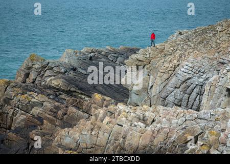 L'homme se tenait sur les falaises de la côte rocheuse près de Rhocolyn sur le chemin de la côte du pays de Galles, Anglesey, au nord du pays de Galles Banque D'Images