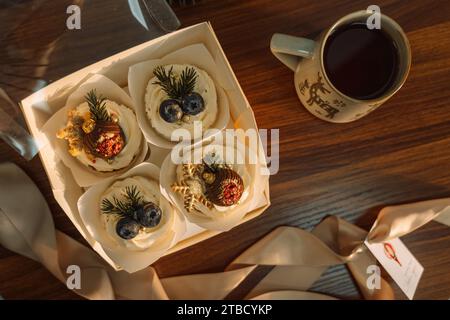 Délicieux cupcakes dans une boîte décorée de chocolat en forme de décorations d'arbre de Noël avec une tasse de café Banque D'Images