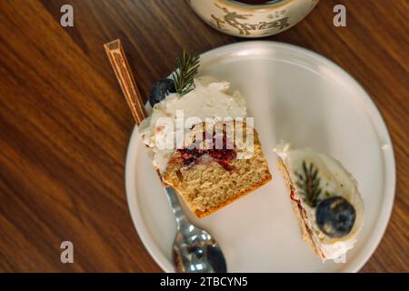 Demi-cupcakes avec garniture de fruits décorée de baies avec une branche d'arbre de Noël sur une assiette blanche Banque D'Images