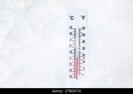 Thermomètre avec échelle celsius et farenheit placé dans une neige montrant la température chaude hivernale Banque D'Images