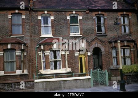 Années 1970, maisons historiques victoriennes avec terrasse, dont une avec une porte d'entrée jaune moderne et des balustrades et une porte vert clair, Angleterre, Royaume-Uni. Banque D'Images