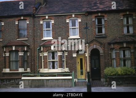 Années 1970, maisons historiques victoriennes avec terrasse, dont une avec une porte d'entrée jaune moderne et des balustrades et une porte vert clair, Angleterre, Royaume-Uni. Banque D'Images