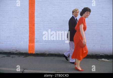 Cowes week Sailing Regatta, un couple se rend au Royal Yacht Squadron club House après la ligne de départ verticale rouge sur le mur du Royal Corinthian Yacht Club, (maintenant le Royal Ocean Racing Club) pour la fin du dîner dansant de la semaine Cowes. La ligne verticale rouge marque la ligne de départ (elle s'aligne avec le mât sur le mur de mer pour créer la ligne. Cowes, île de Wight, Angleterre vers août 1985 1980 Royaume-Uni HOMER SYKES Banque D'Images
