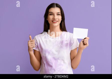 Femme enceinte avec le papier de vote montrant le pouce vers le haut sur fond lilas Banque D'Images