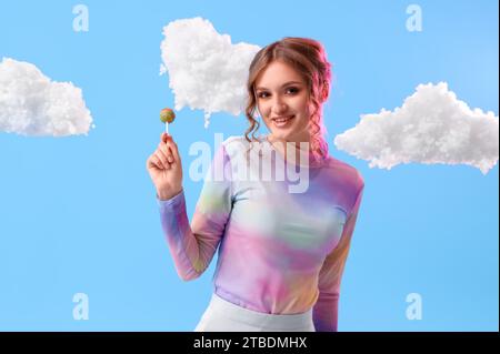 Jeune femme avec sucette et nuages blancs sur fond bleu Banque D'Images