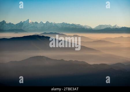 Montagnes couvertes de brume au premier plan avec chaîne de montagnes de l'Himalaya en arrière-plan, vue depuis Pangot, Inde Banque D'Images
