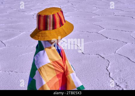 Gros plan portrait de garçon sur son côté avec un drapeau whipala drapé sur son corps et une casquette colorée regardant les Salinas grandes à Jujuy. Espace de copie Banque D'Images