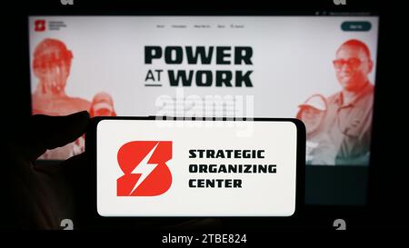 Personne tenant un téléphone portable avec le logo de la coalition syndicale Strategic Organizing Center (SOC) en face de la page Web. Concentrez-vous sur l'affichage du téléphone. Banque D'Images