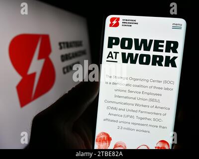 Personne tenant un téléphone portable avec la page Web de la coalition syndicale Strategic Organizing Center (SOC) avec logo. Concentrez-vous sur le centre de l'écran du téléphone. Banque D'Images