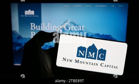 Personne détenant un téléphone portable avec le logo de la société d'investissement américaine New Mountain Capital (NMC) devant la page Web de l'entreprise. Concentrez-vous sur l'affichage du téléphone. Banque D'Images