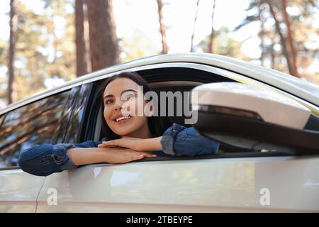 Heureuse jeune femme regardant par la fenêtre de la voiture, vue de l'extérieur. Bon voyage Banque D'Images