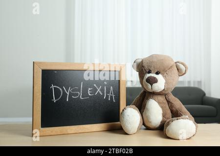 Ours en peluche et petit tableau noir avec mot Dyslexia sur une table en bois à l'intérieur Banque D'Images