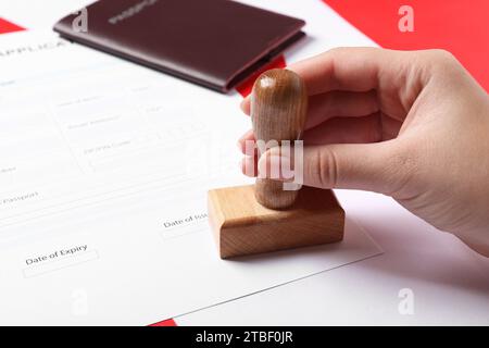 Immigration au Canada. Femme tamponnant le formulaire de demande de visa sur le drapeau, closeup Banque D'Images