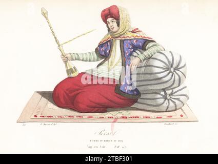 Courtisane du harem royal, Perse. Beauté en turban, voile, veste doublée de fourrure, jupes, couchée sur un divan, fumant une pipe narguilée. Perse, Femme du Harem du Roi. D'après une illustration de James Baillie Fraser. Gravure sur acier coloriée à la main par Choubard d'après une illustration de Leopold Massard de Collection de portraits et costumes des différents peuples qui habitent les cinq parties du monde, Armand-Aubree, Paris, 1837. Banque D'Images