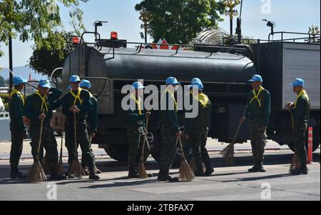 De jeunes représentants de l'armée royale thaïlandaise aident les autres lors d'une journée nationale de nettoyage à Nakhon Phanom, en Thaïlande, en Asie du Sud-est. Le 5 décembre est une fête nationale car il commémore l'anniversaire du défunt roi Bhumibol Adulyadej, Rama 9. Cet événement commence par des participants en uniforme qui défilent pour des photos et de courts discours, suivis par tous ceux qui utilisent des brosses brindilles et des camions-citernes pour nettoyer les rues. Cette journée est connue sous le nom de fête des pères en Thaïlande. Banque D'Images