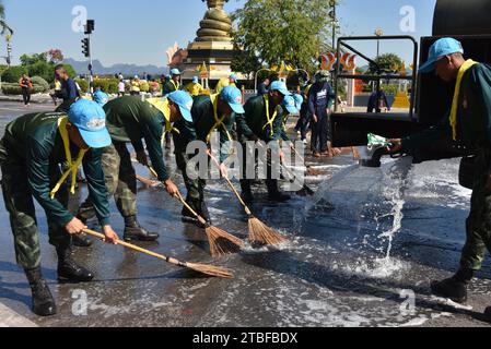 De jeunes représentants de l'armée royale thaïlandaise aident les autres lors d'une journée nationale de nettoyage à Nakhon Phanom, en Thaïlande, en Asie du Sud-est. Le 5 décembre est une fête nationale car il commémore l'anniversaire du défunt roi Bhumibol Adulyadej, Rama 9. Cet événement commence par des participants en uniforme qui défilent pour des photos et de courts discours, suivis par tous ceux qui utilisent des brosses brindilles et des camions-citernes pour nettoyer les rues. Cette journée est connue sous le nom de fête des pères en Thaïlande. Banque D'Images